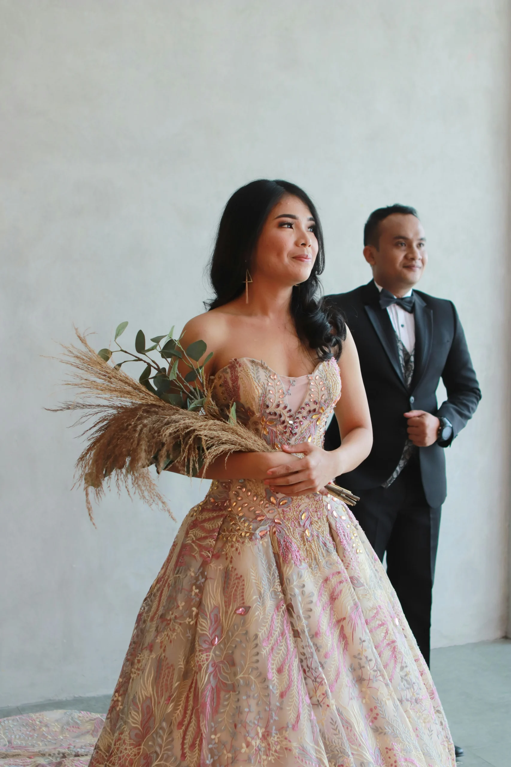 a woman in a dress standing next to a man in a tuxedo