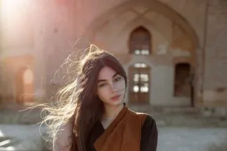 a woman with long hair standing in front of a building