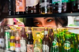 a woman looking at a shelf of beer bottles